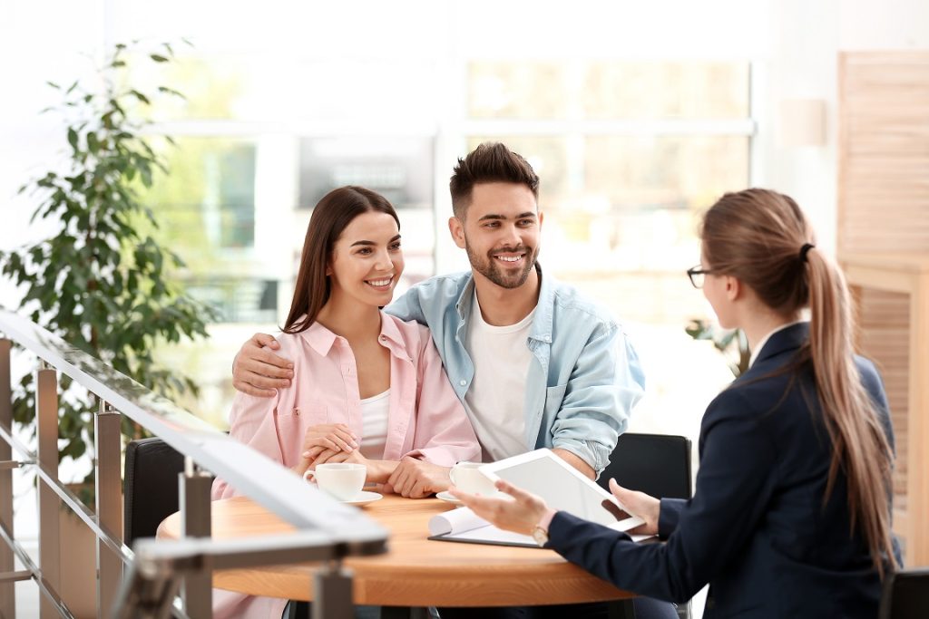 Female insurance agent working with young couple in office