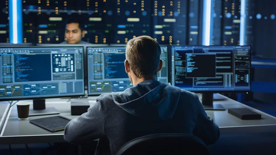 IT Specialist Works on Personal Computer with Screens Showing So